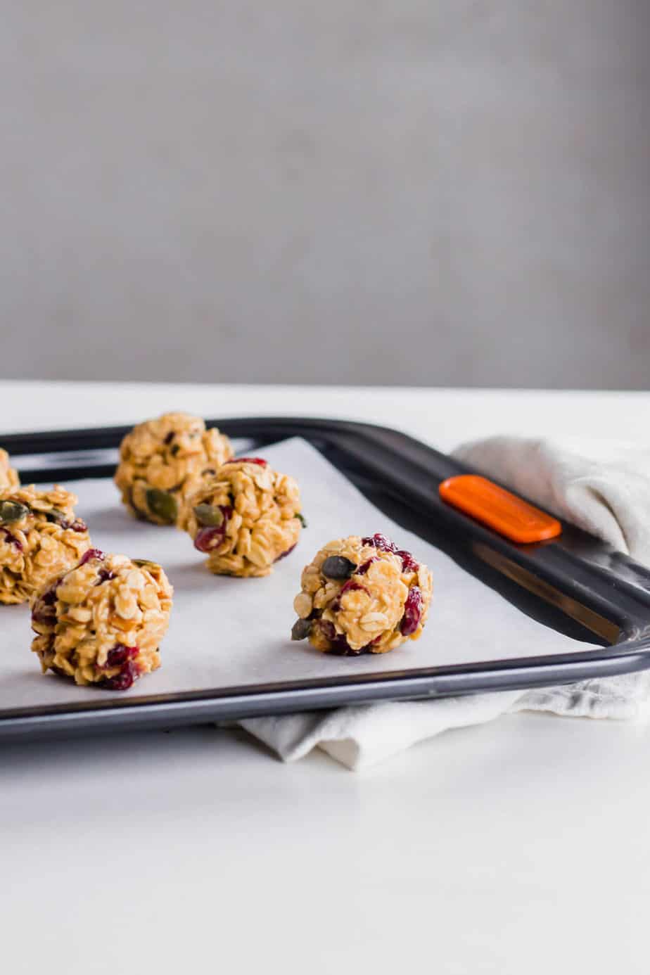 Healthy oat bliss balls with cranberries on a baking tray lined with parchment paper.