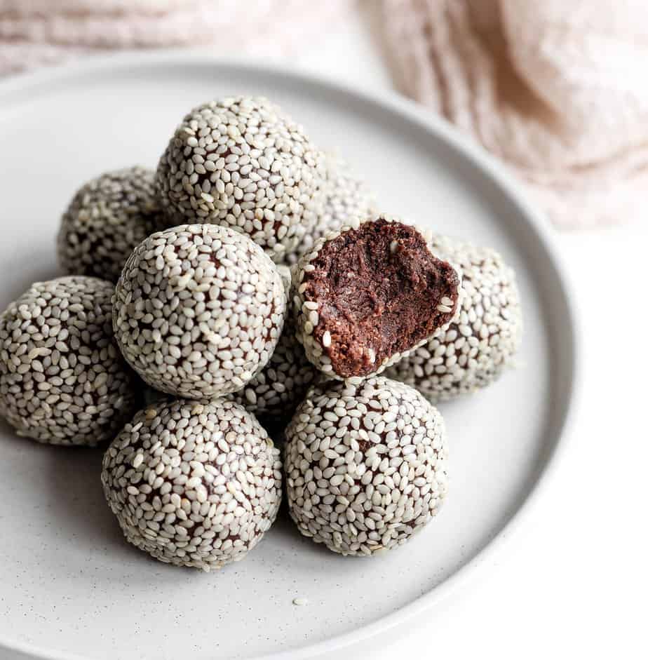 Sesame seed coated energy balls on a light gray plate.