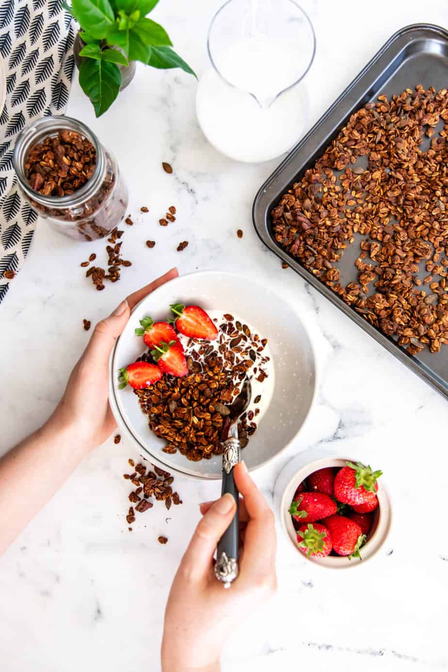 A bowl of banana bread granola served with milk and fresh strawberries.