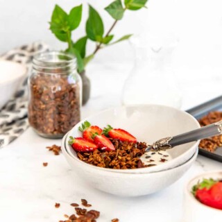 A bowl of banana bread granola topped with fresh strawberries.