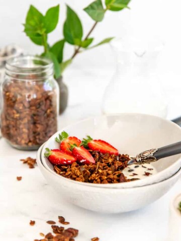 A bowl of banana bread granola topped with fresh strawberries.