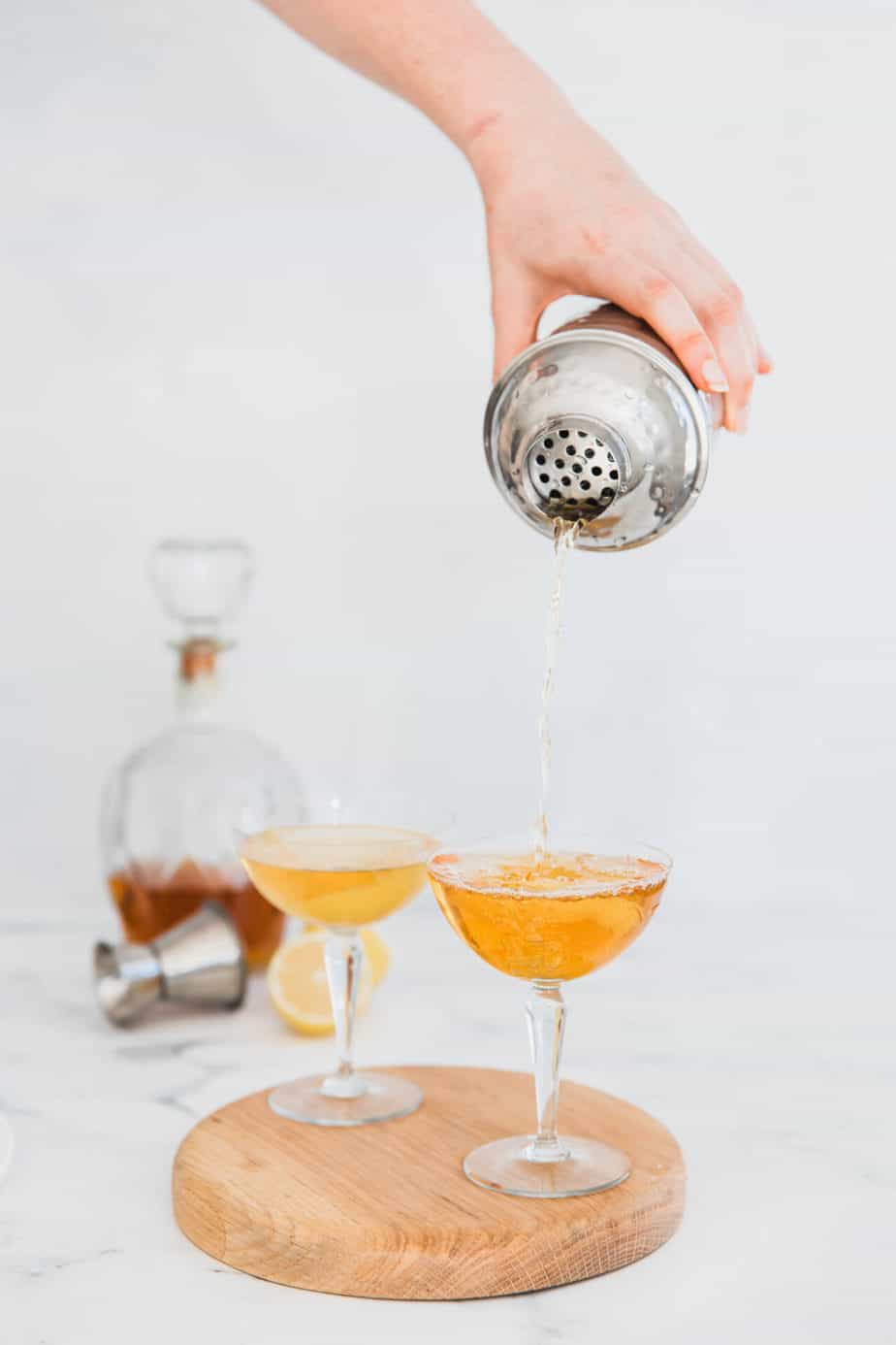 Cocktail shaker pouring a mixer into bourbon.