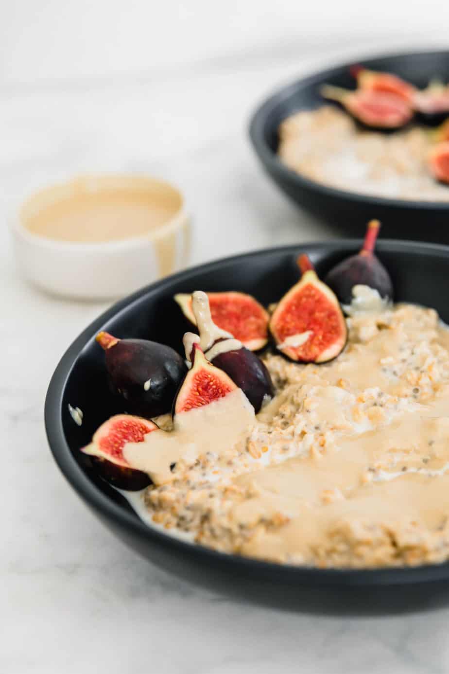 Figs on top of oatmeal in a black bowl.
