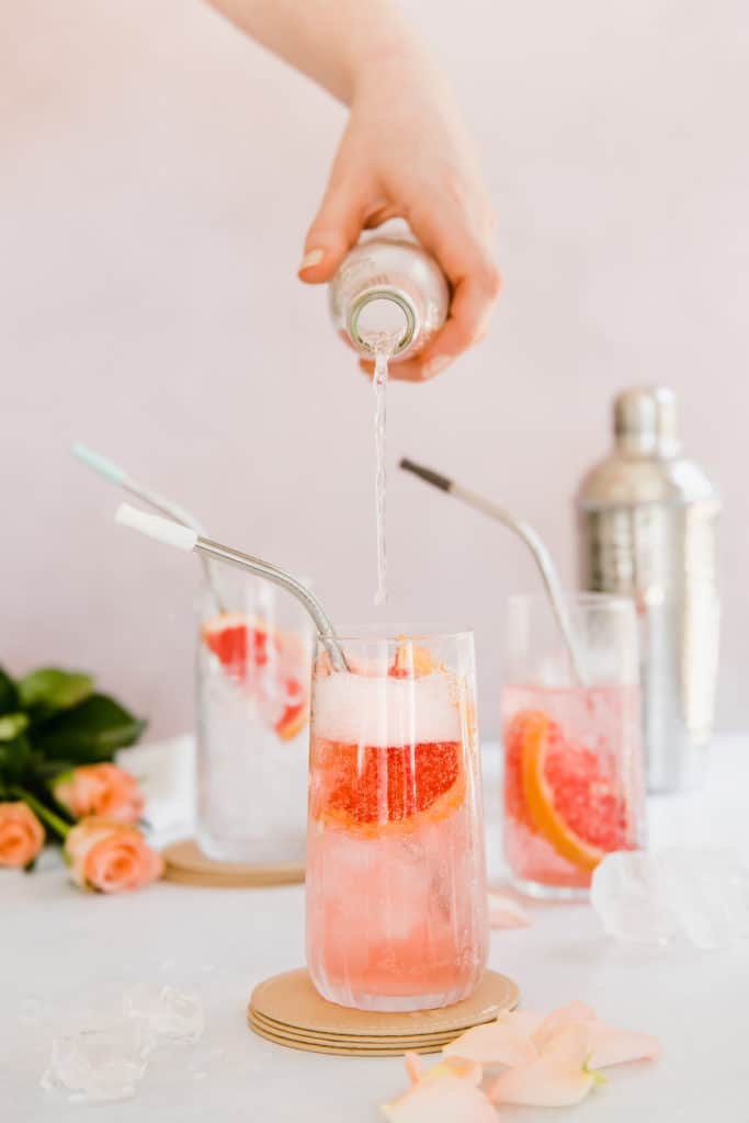grapefruit gin spritzer on pink background with fresh grapefruit slices