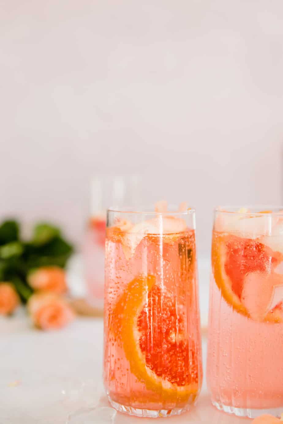 A mixed cocktail with fresh grapefruit and rose petals.