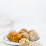 carrot cake energy balls without dates rolled in coconut on white plate
