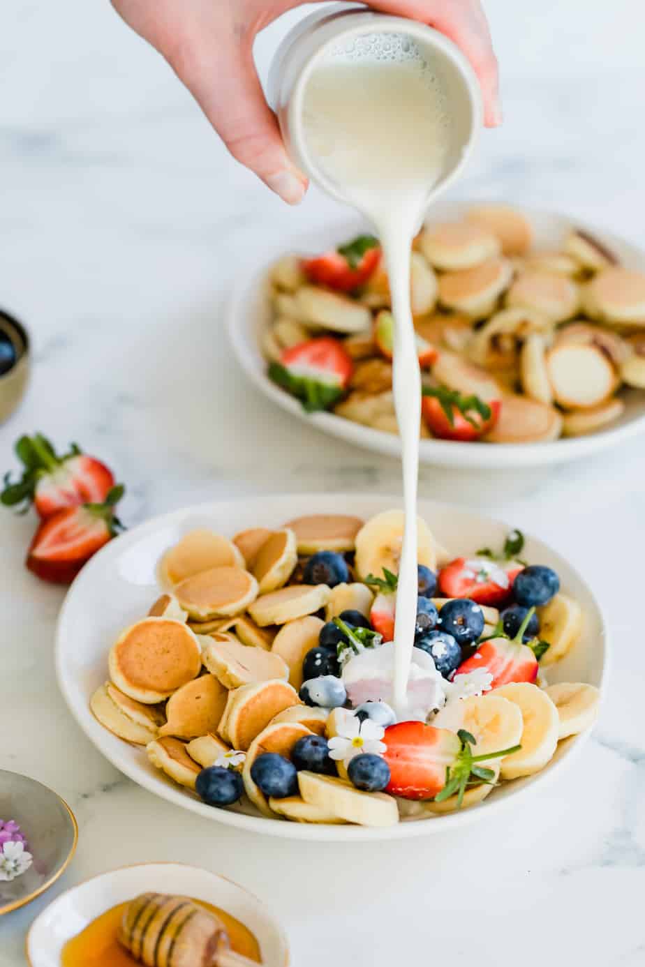 Milk pouring over Easy Pancake Cereal in a bowl with berries
