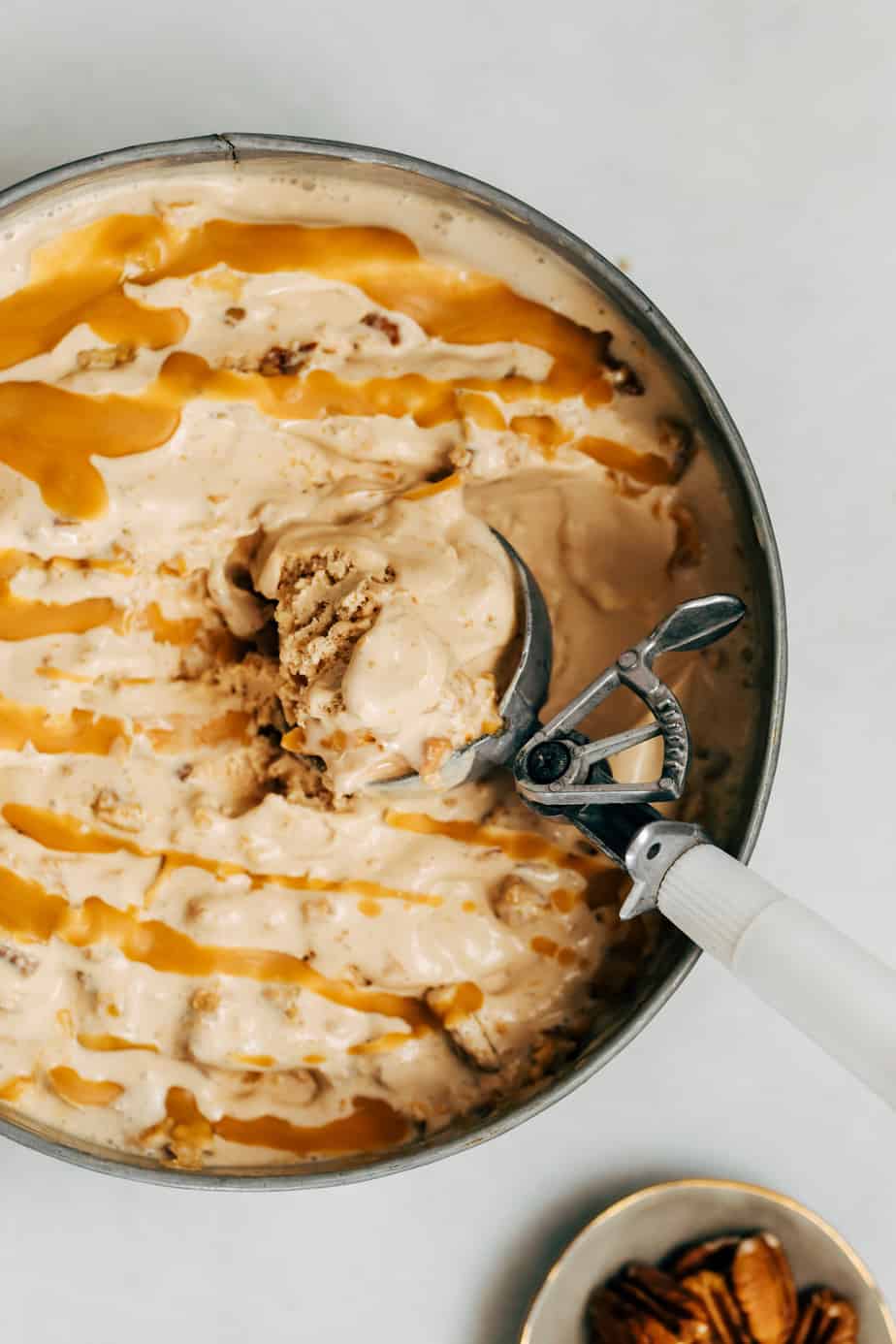Caramel ice cream with a white ice cream scoop.