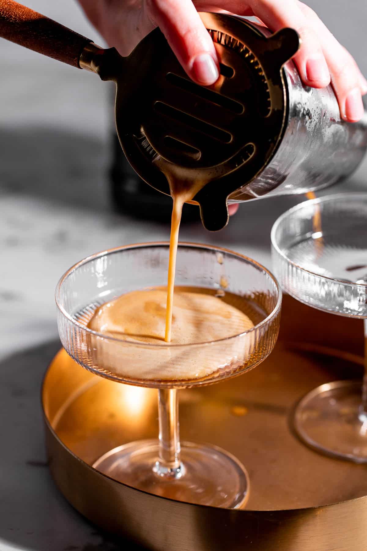 A espresso martini being poured into a martini glass.