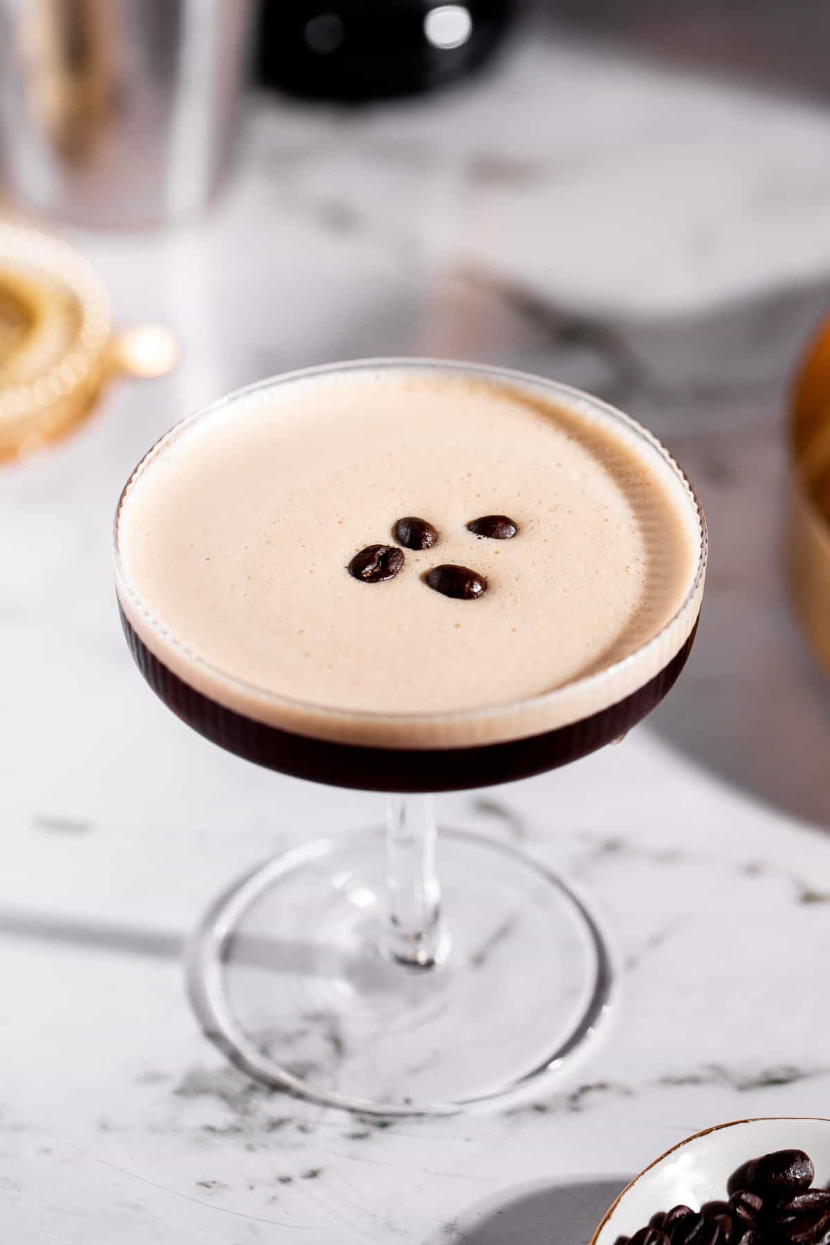 A tequila espresso martini on a gold tray garnished with coffee beans.