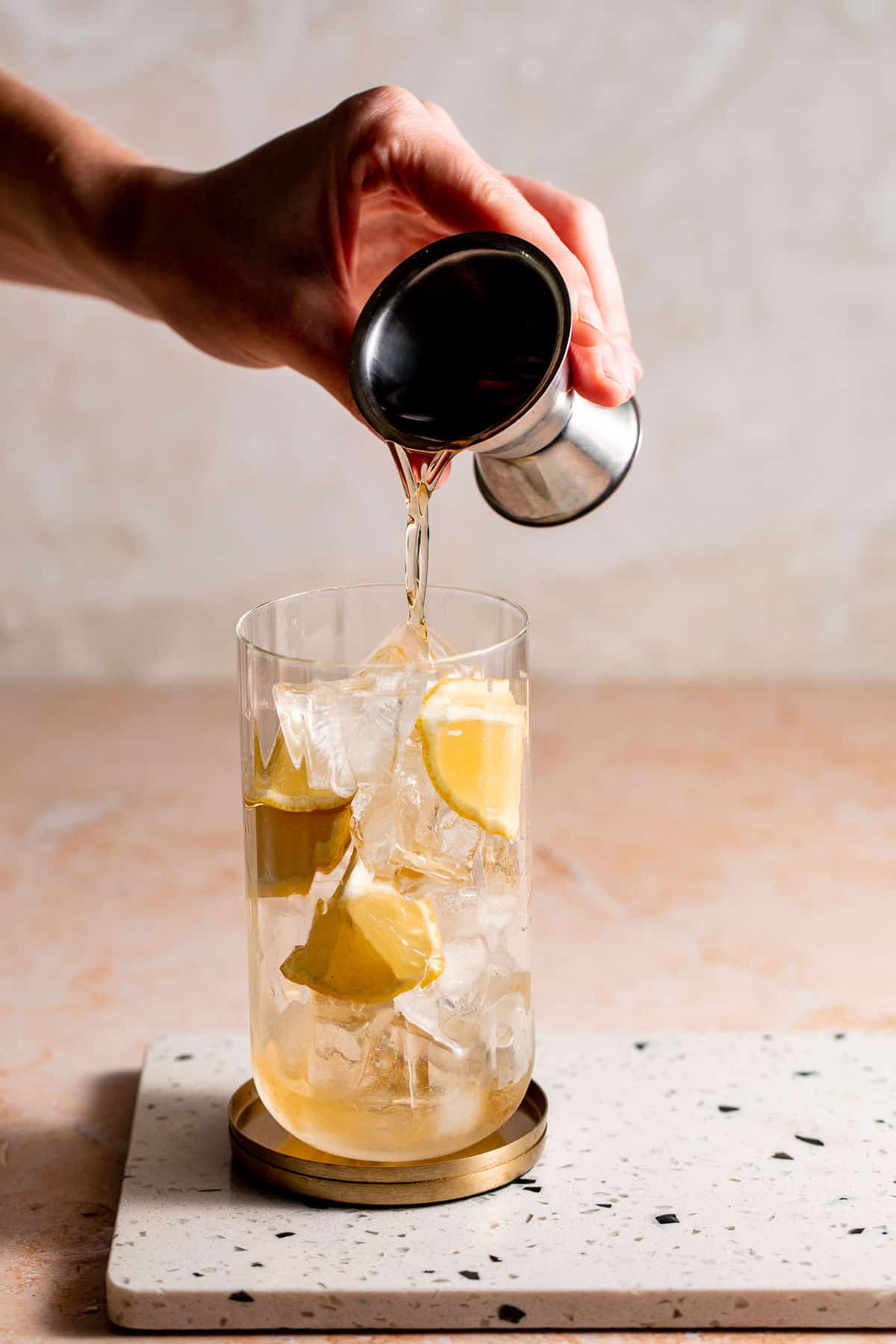 Whiskey pouring into a highball glass filled with ice.