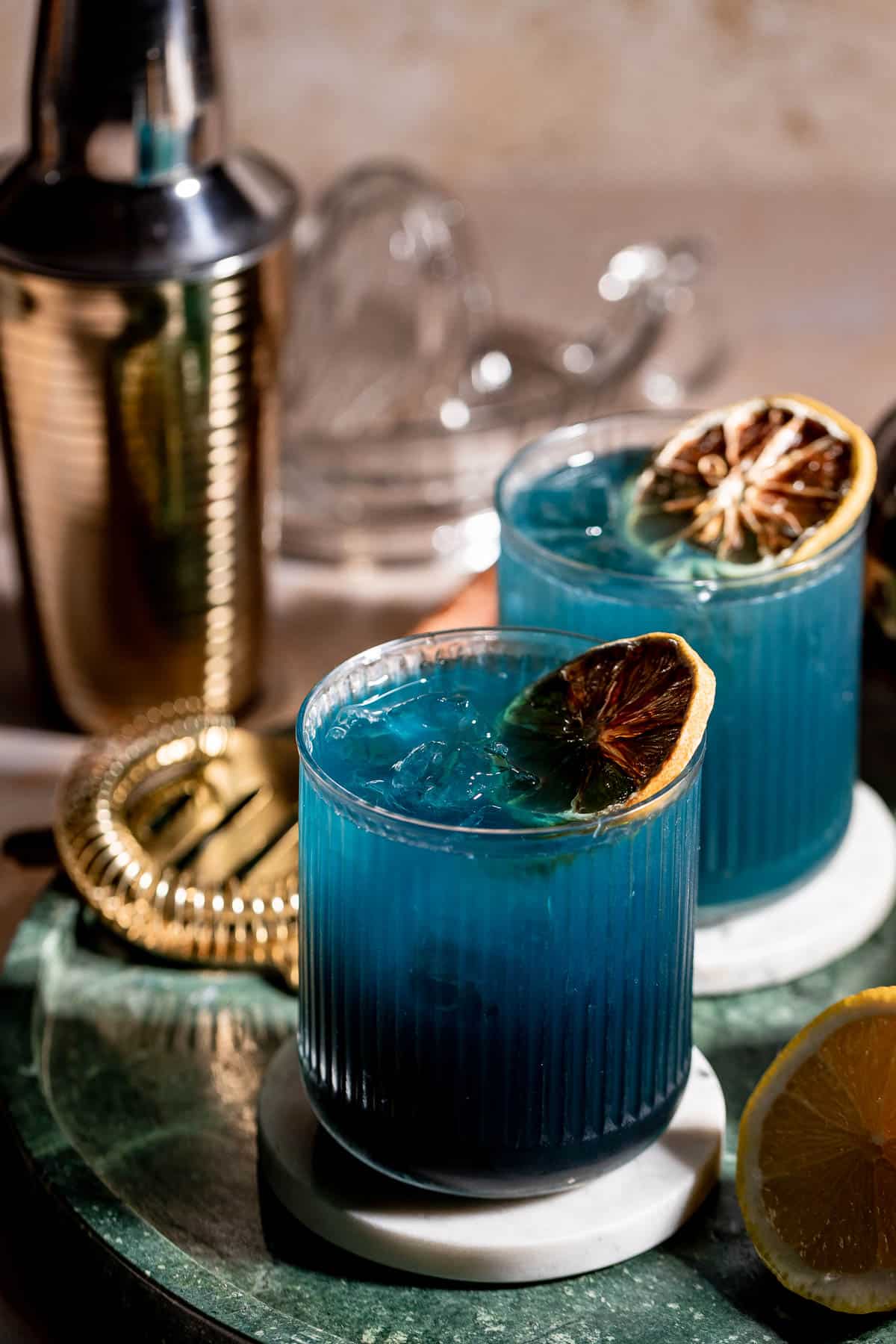 two glasses of black opal cocktail on green marble
