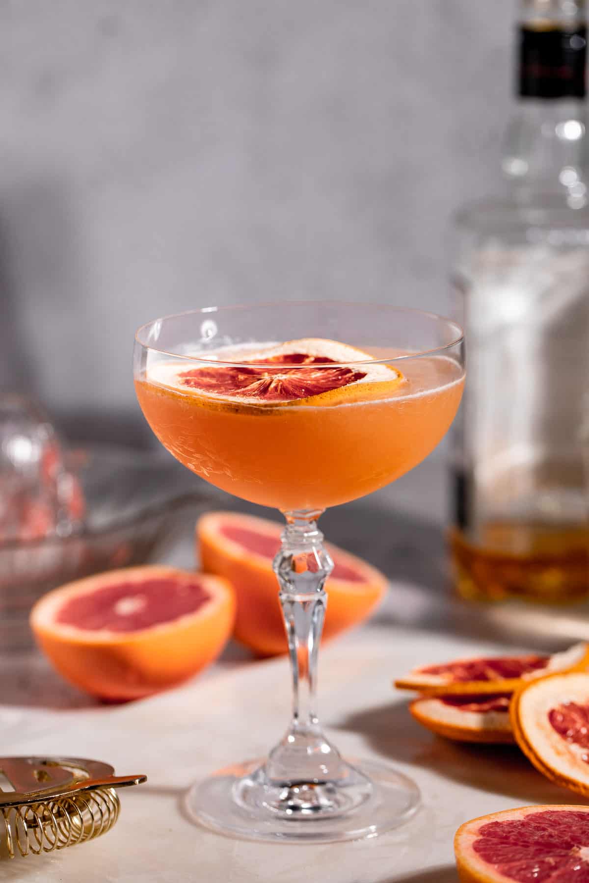 A Brown Derby Cocktail served in a stemmed glass garnished with a slice of grapefruit.