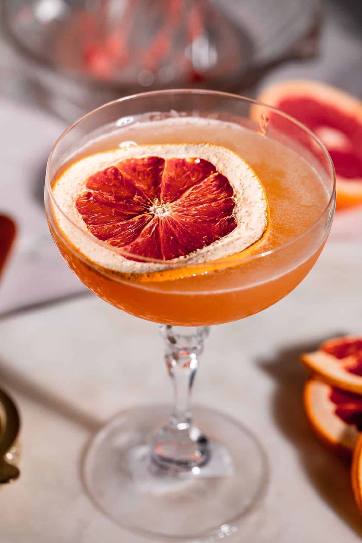 A Brown Derby Cocktail served in a stemmed glass garnished with a slice of grapefruit.