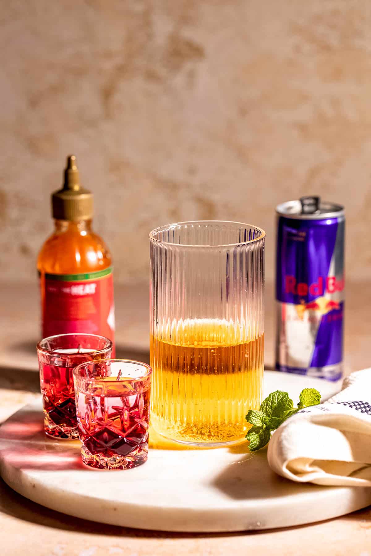 white marble with red bull in glass and two shot glasses