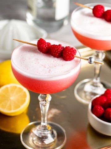 two glasses on gold tray with raspberries