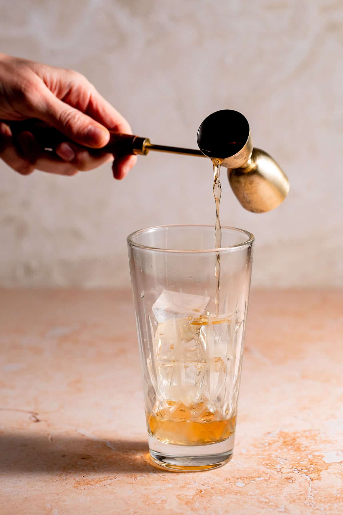 Rum pouring into a glass filled with ice