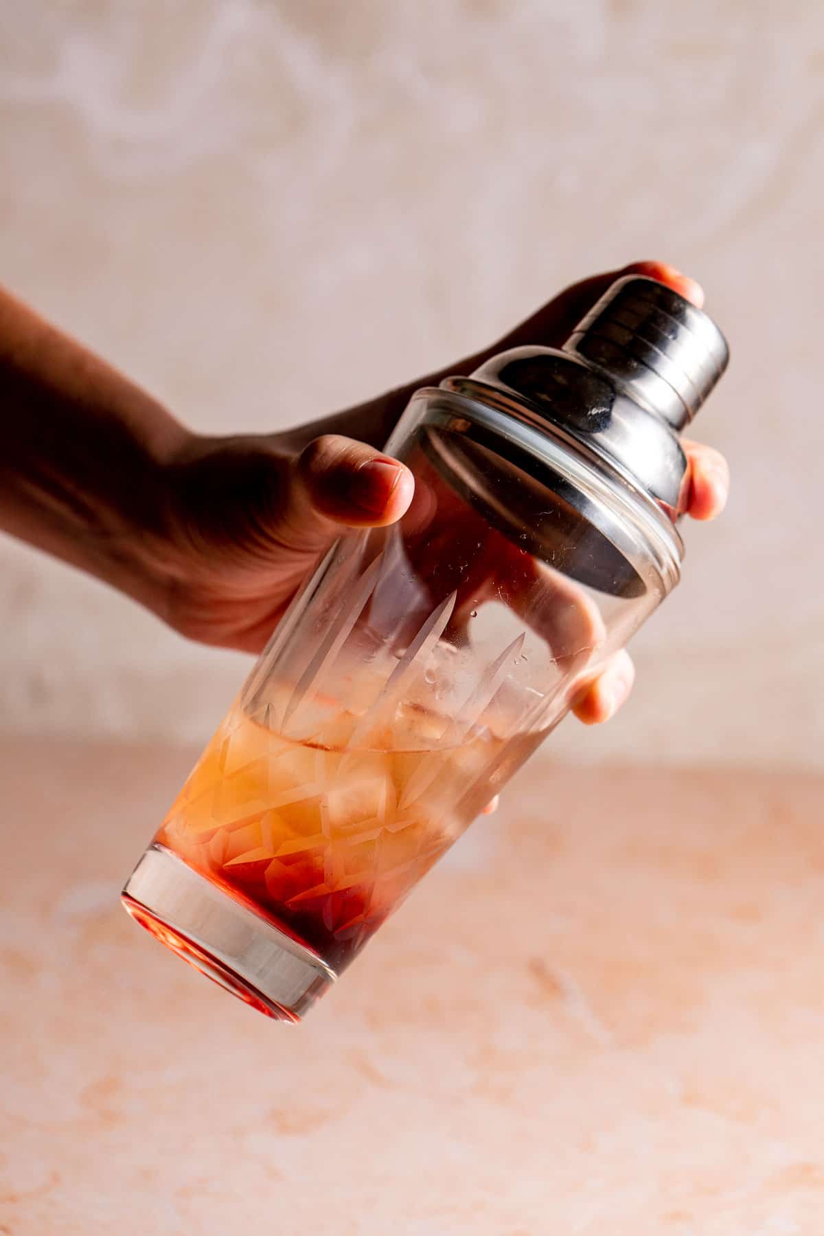 a cocktail shaker filled with ice and orange liquid.