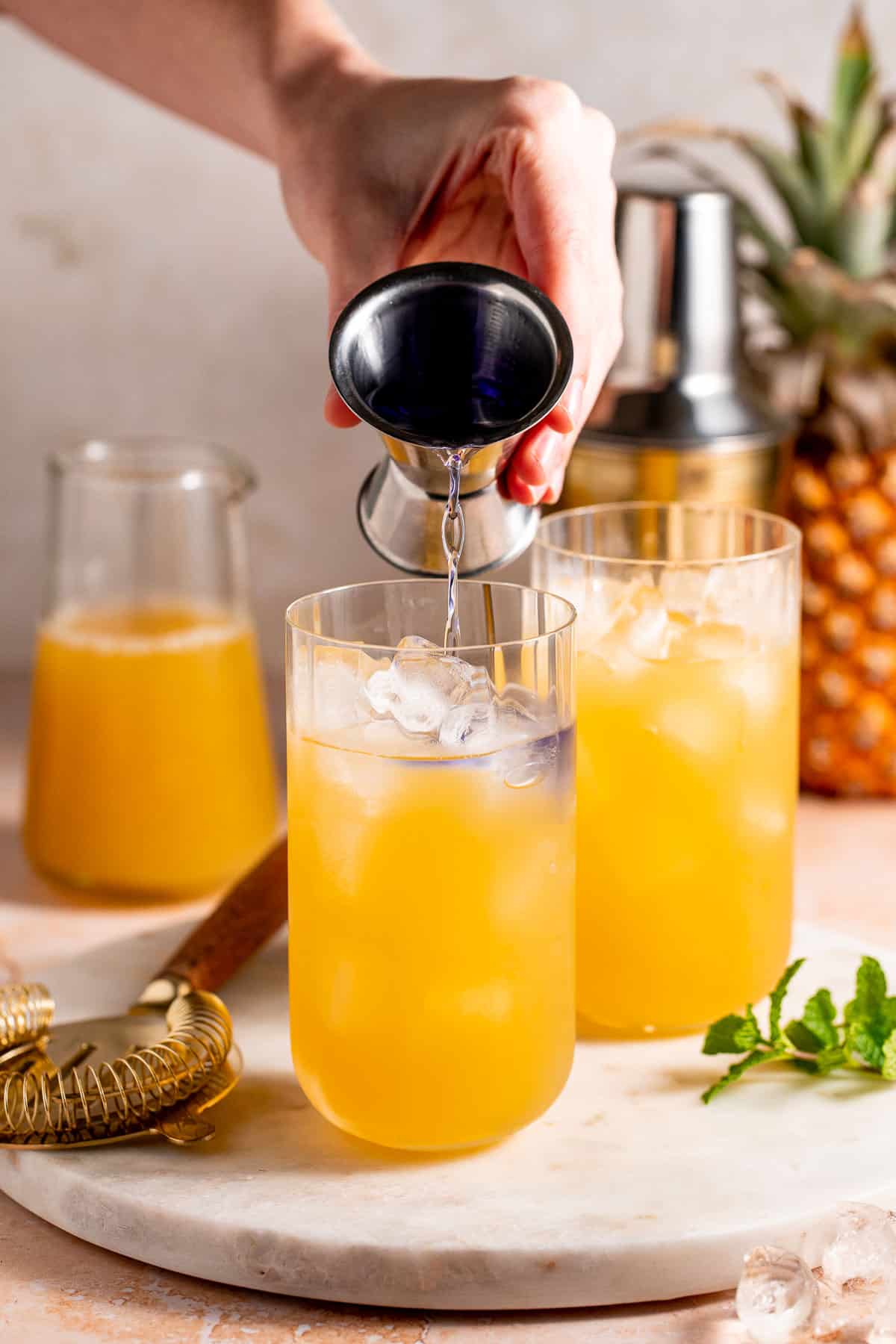 Tequila being added to a glass of juice and ice.