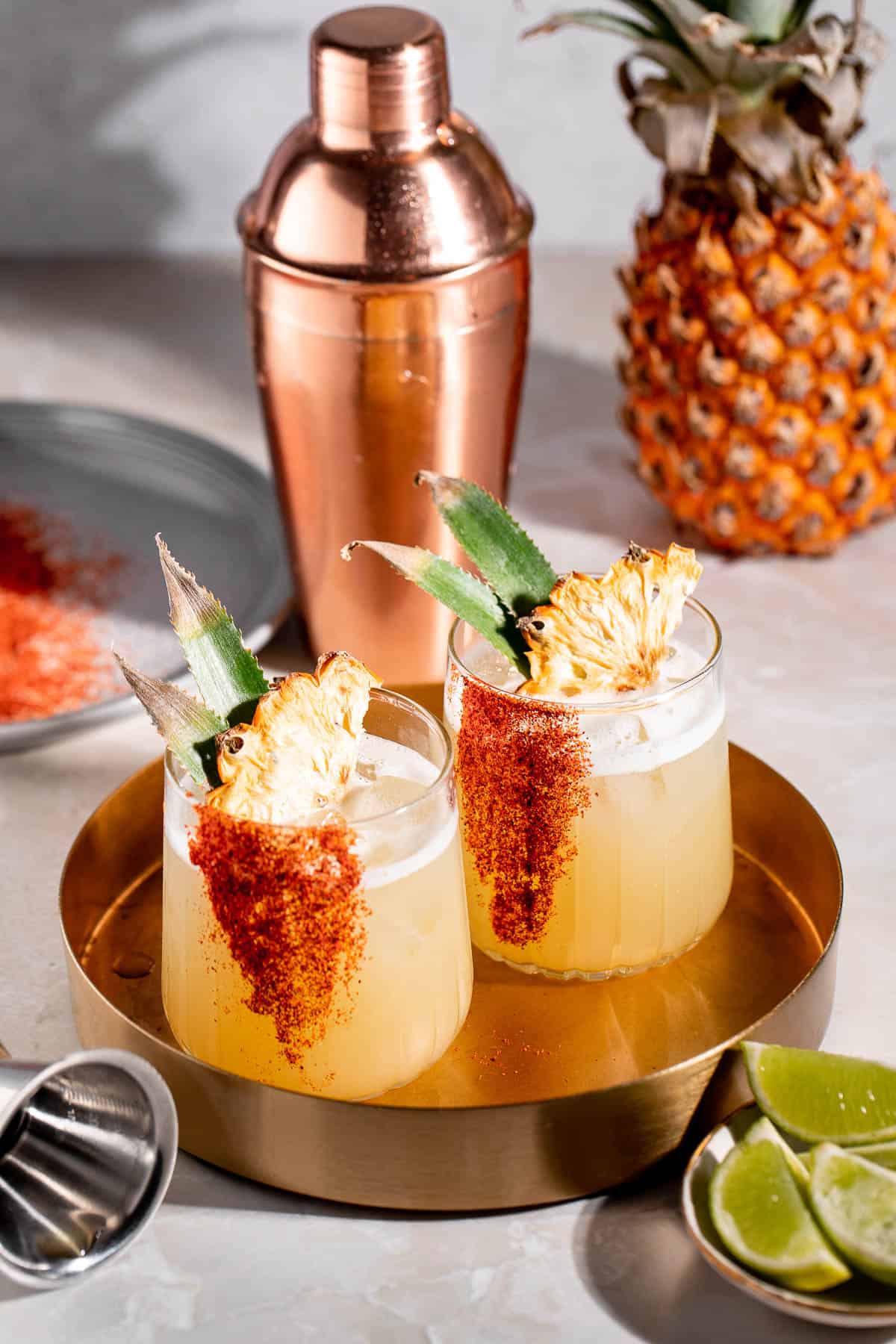 cocktails on gold tray with pineapple and cocktail shaker