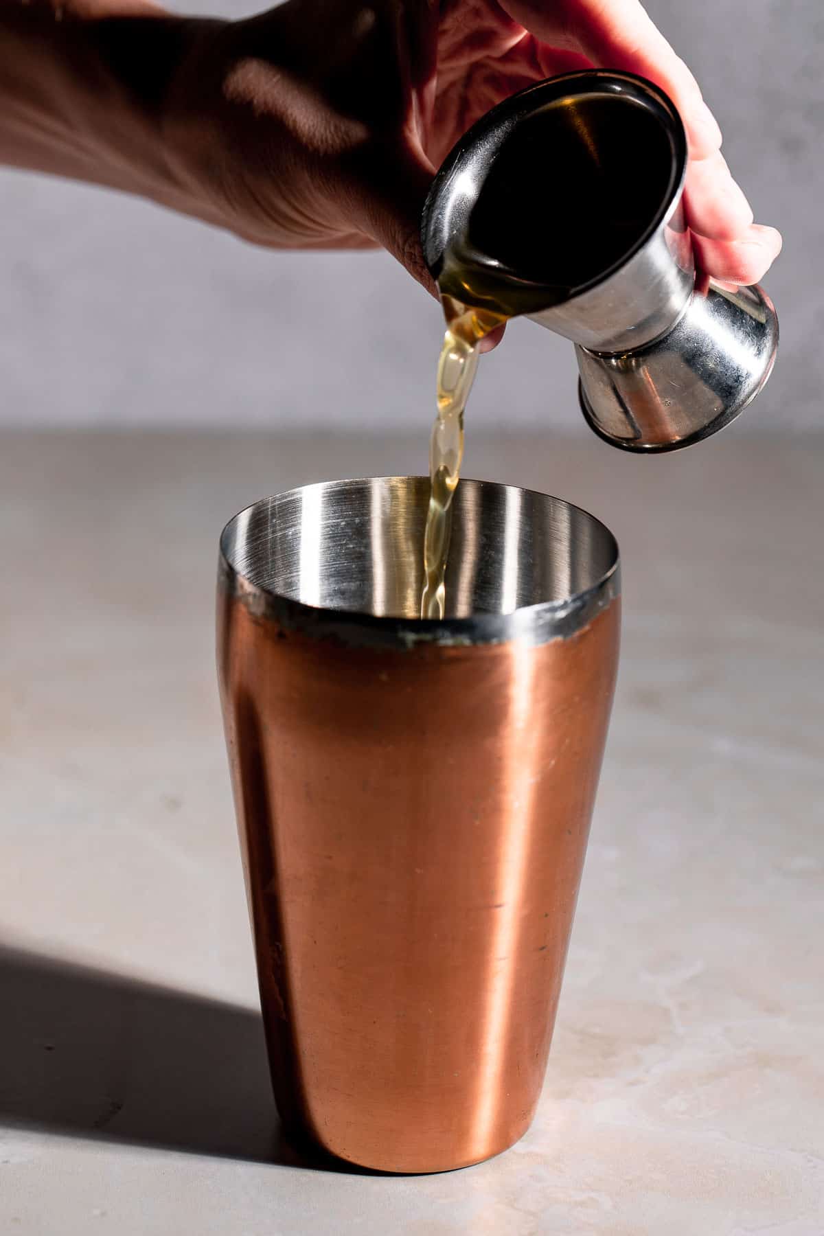 pouring liquor into gold cocktail shaker