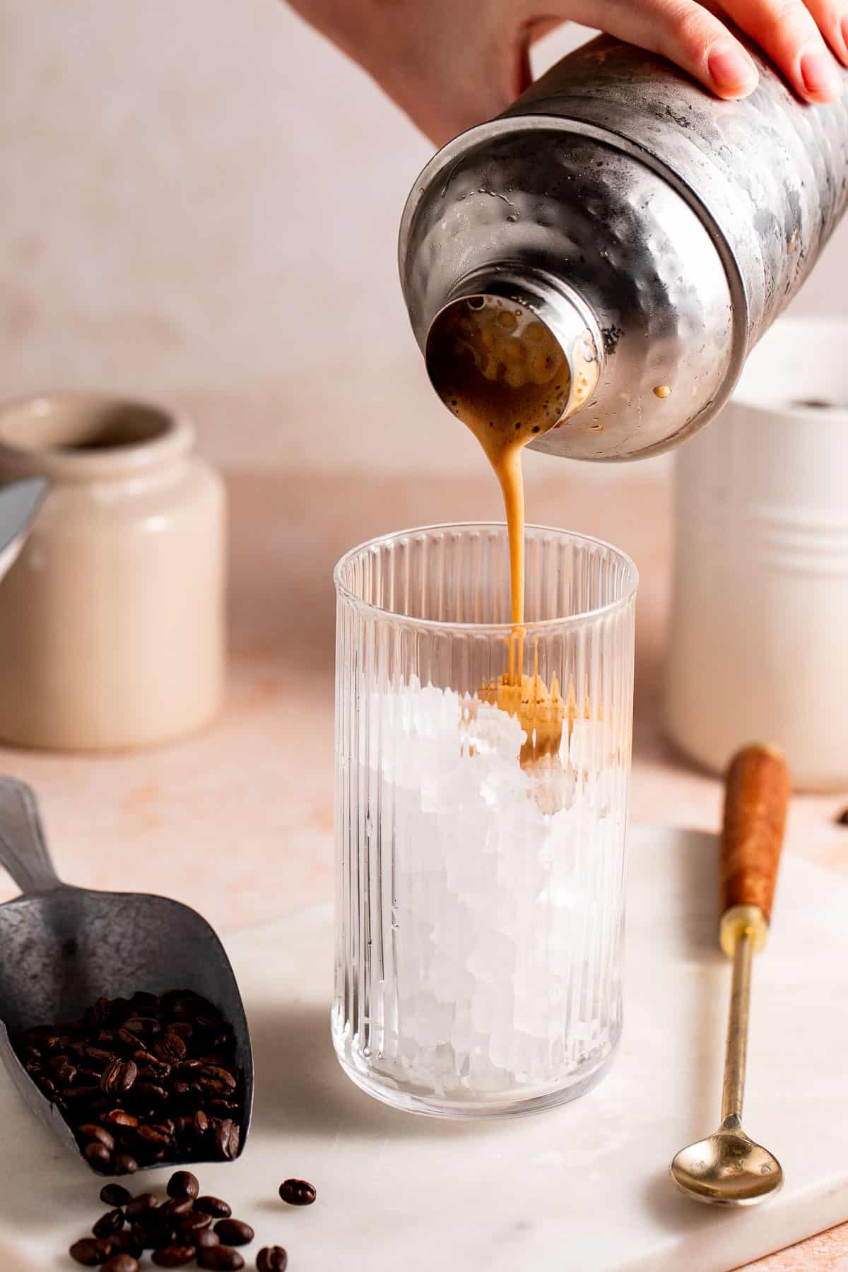 Coffee cocktail pouring into a serving glass filled with ice