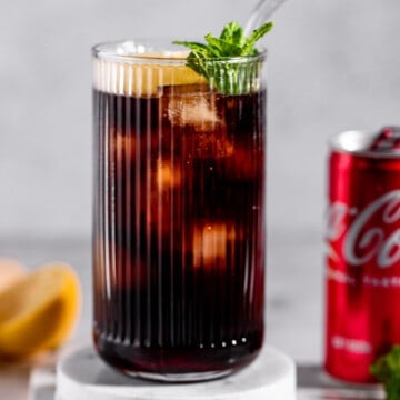 glass with coca cola and grenadine on marble coasters