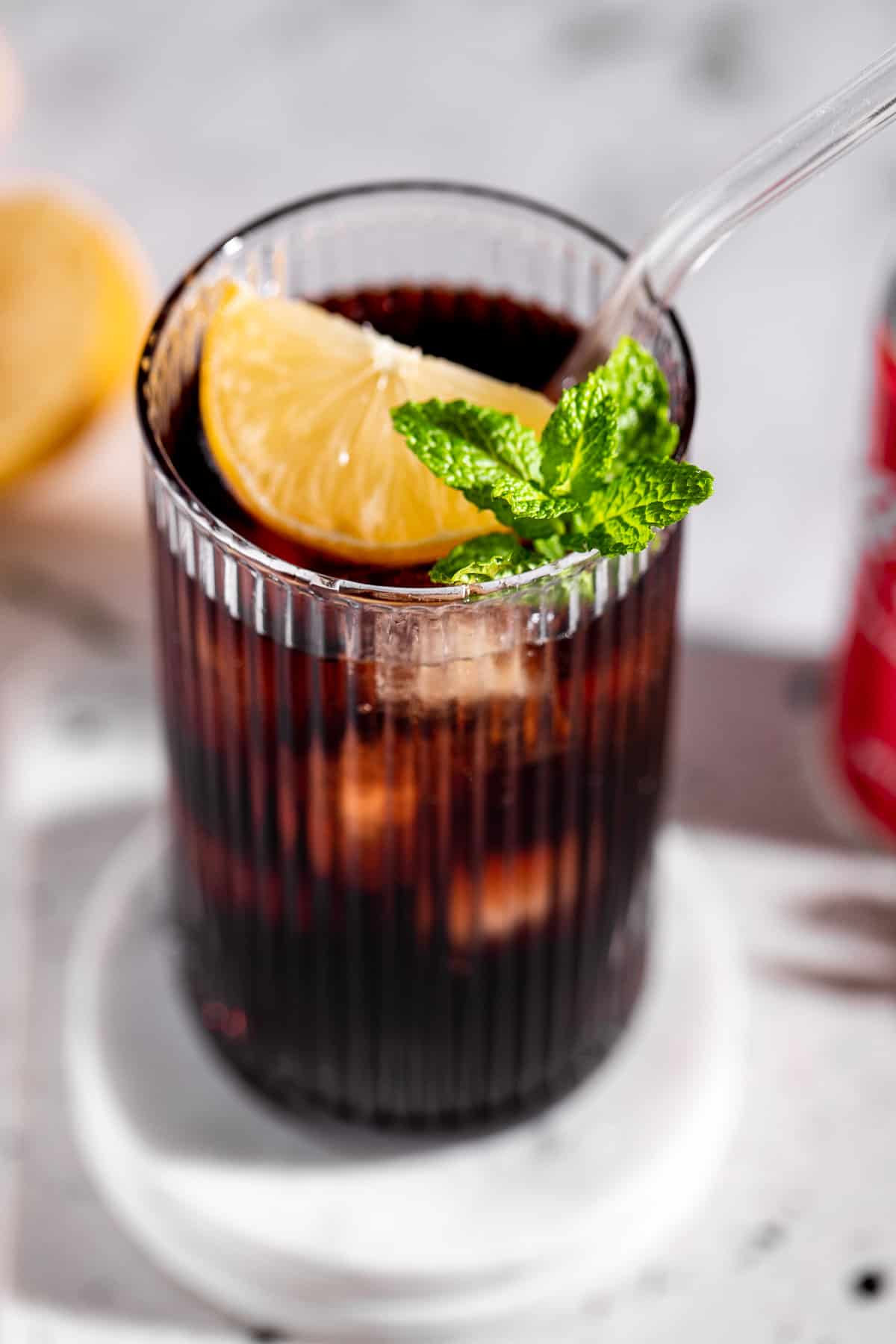 tall highball glass filled with coke and grenadine topped with fresh lemon and mint