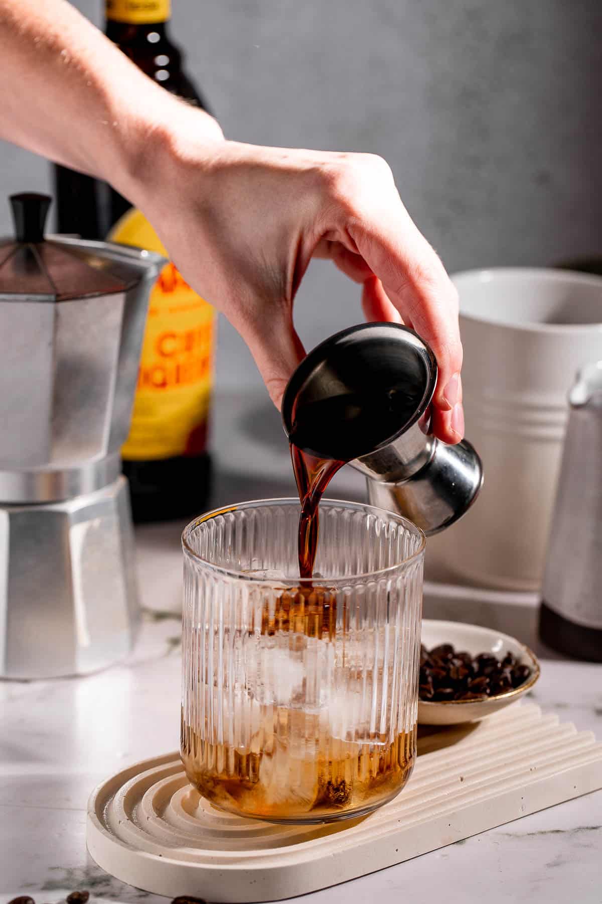 Kahlua pouring into a serving glass filled with ice cubes.