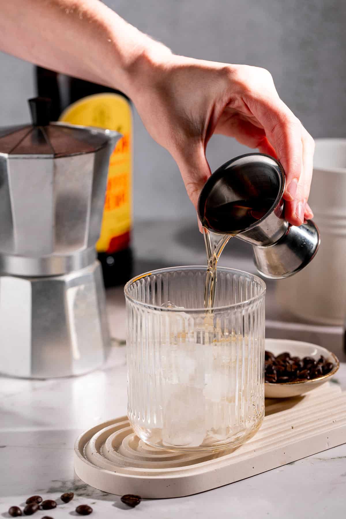 Skrewball whiskey pouring into a serving glass filled with ice cubes.