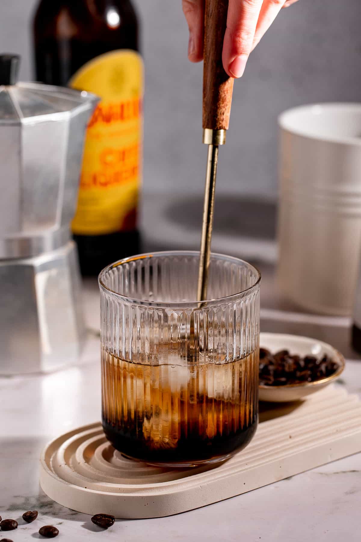 A spoon mixing together the ingredients for a White Russian Screwball Drink.