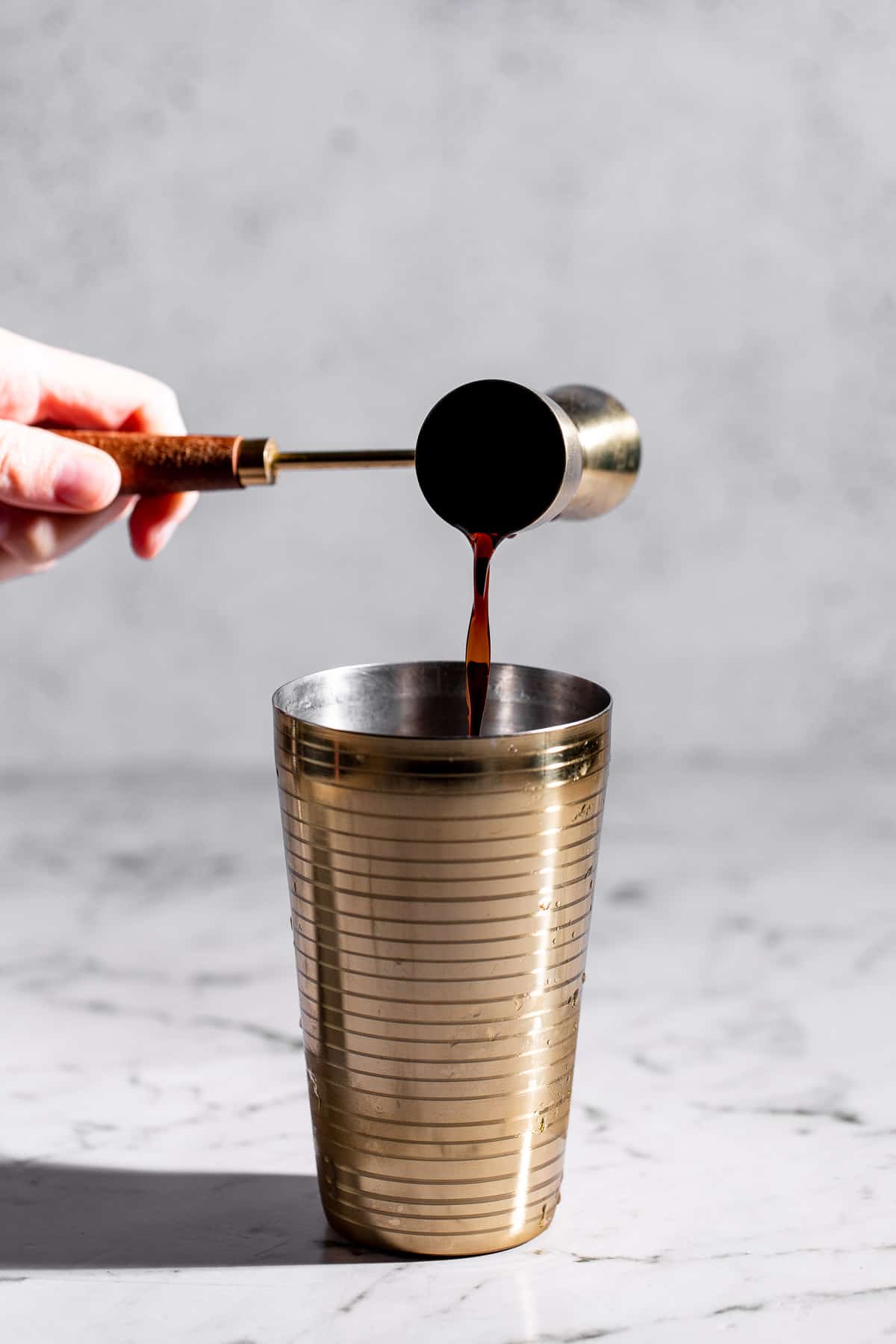 adding coffee liquor to cocktail shaker