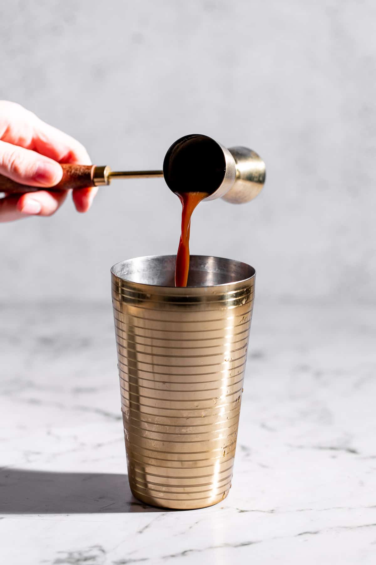 adding espresso shot to gold cocktail shaker