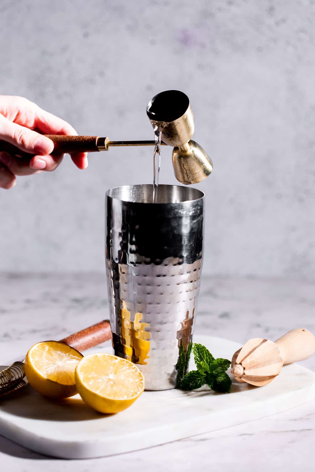 Simple syrup pouring into a cocktail shaker.