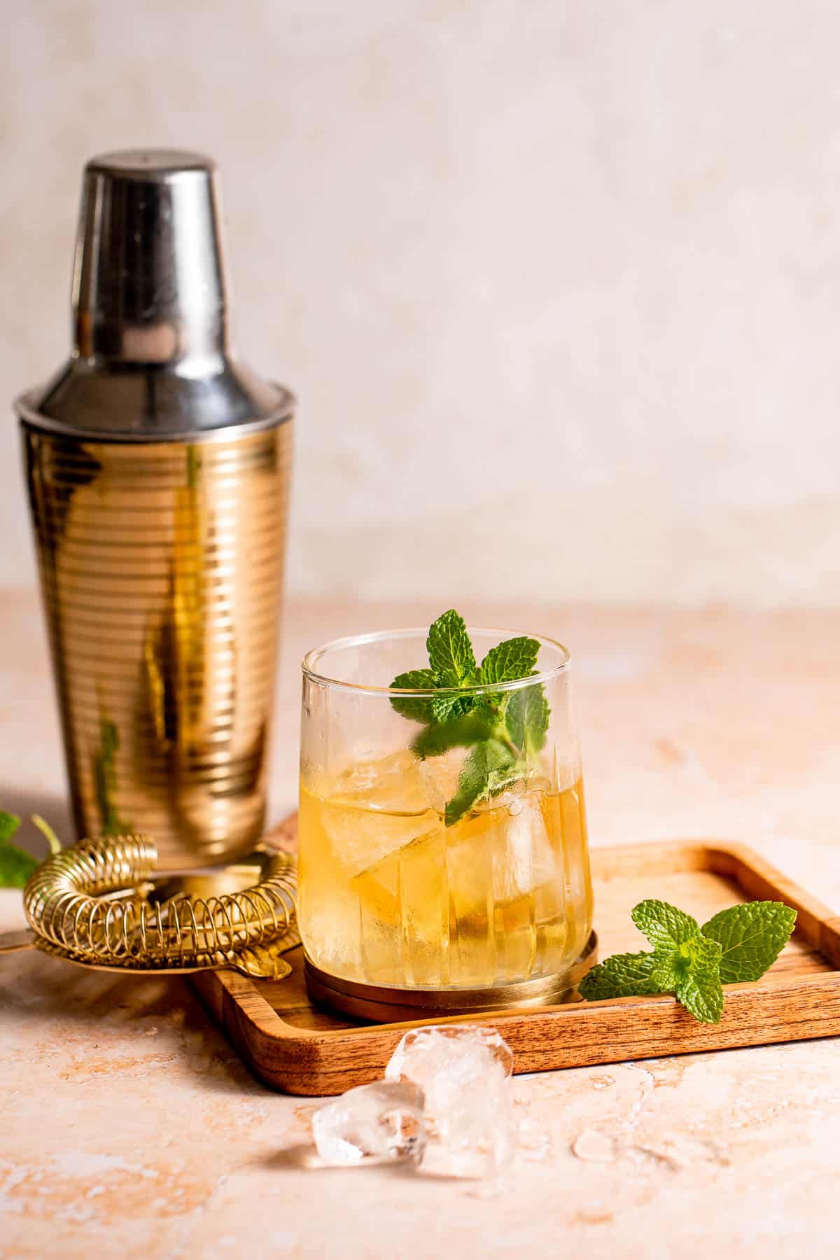 A Stinger Cocktail served with fresh mint on a wooden serving board.