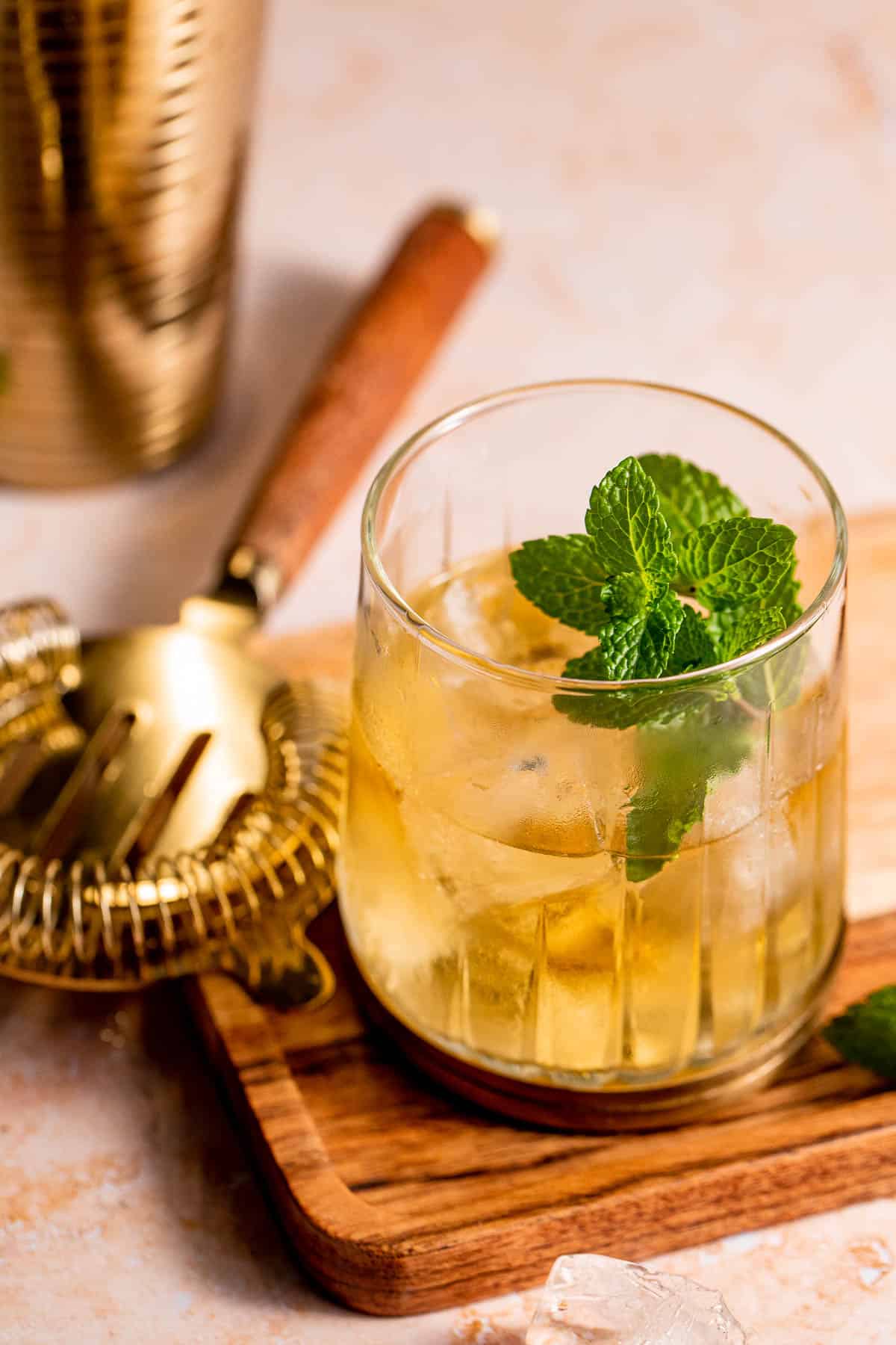 A Stinger Cocktail served with fresh mint and ice on a wooden serving board.