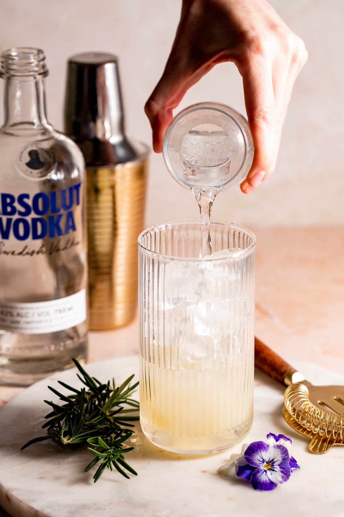 A highball glass filled with ice with soda water pouring into it