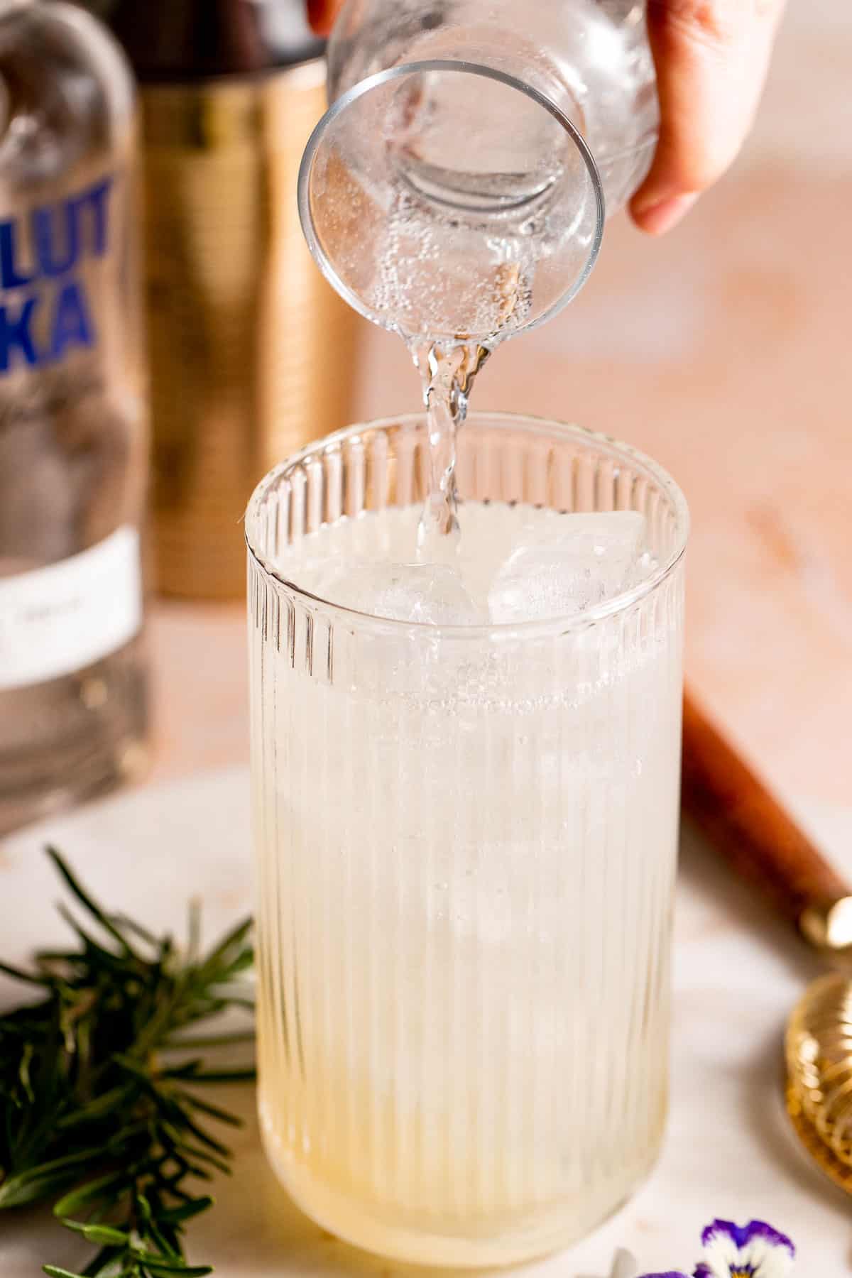 Soda water pouring into a highball cocktail glass
