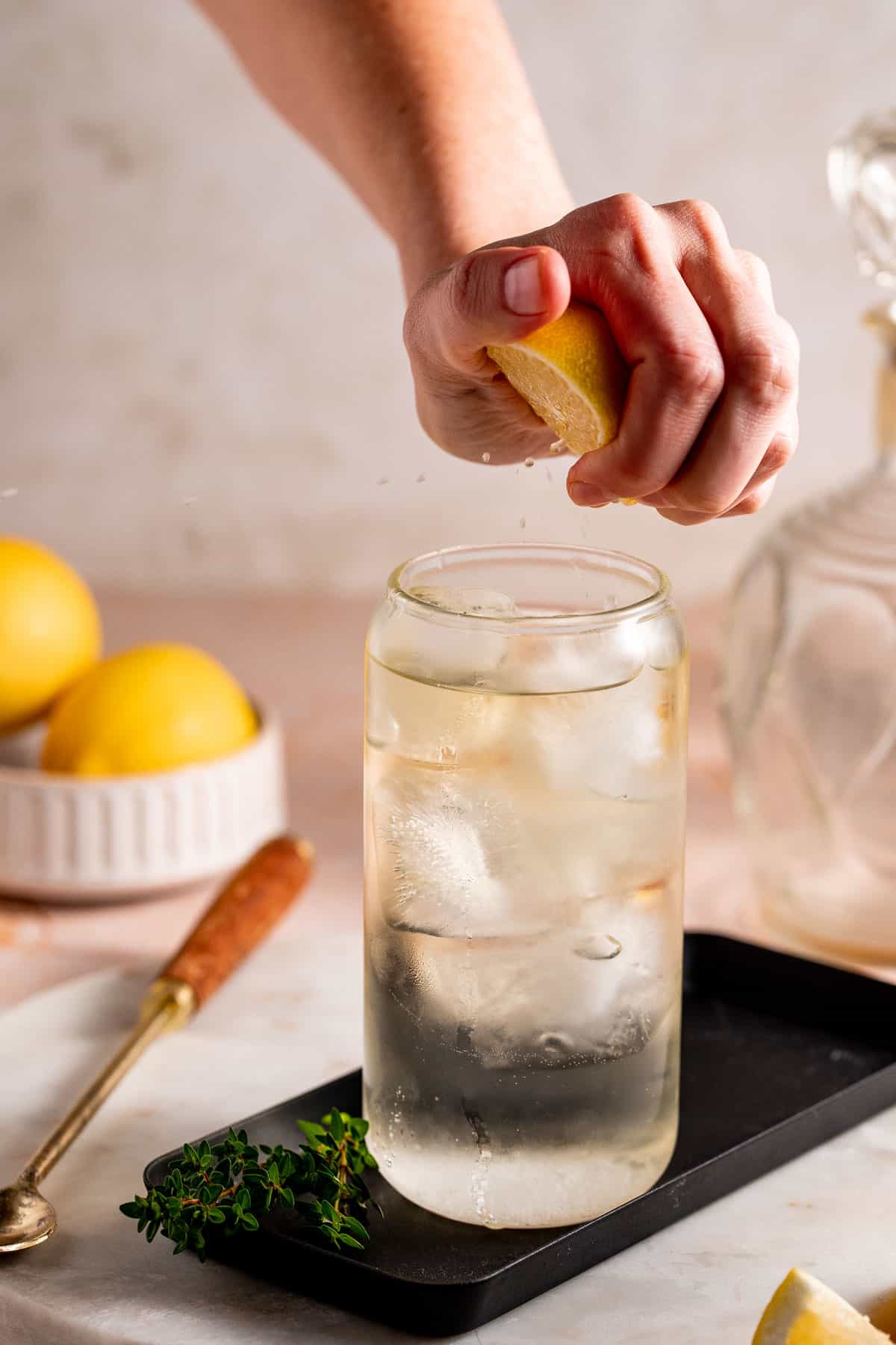 Lemon wedge being squeezed into a drink. 