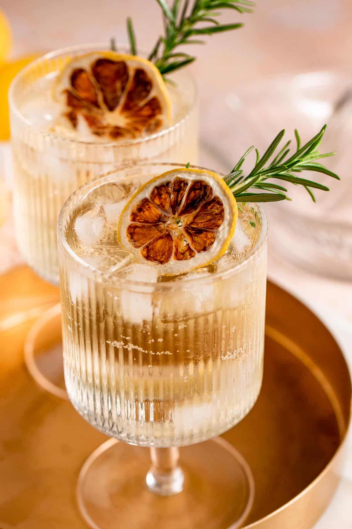 A Whiskey Tonic in a serving glass with ice and fresh herbs.