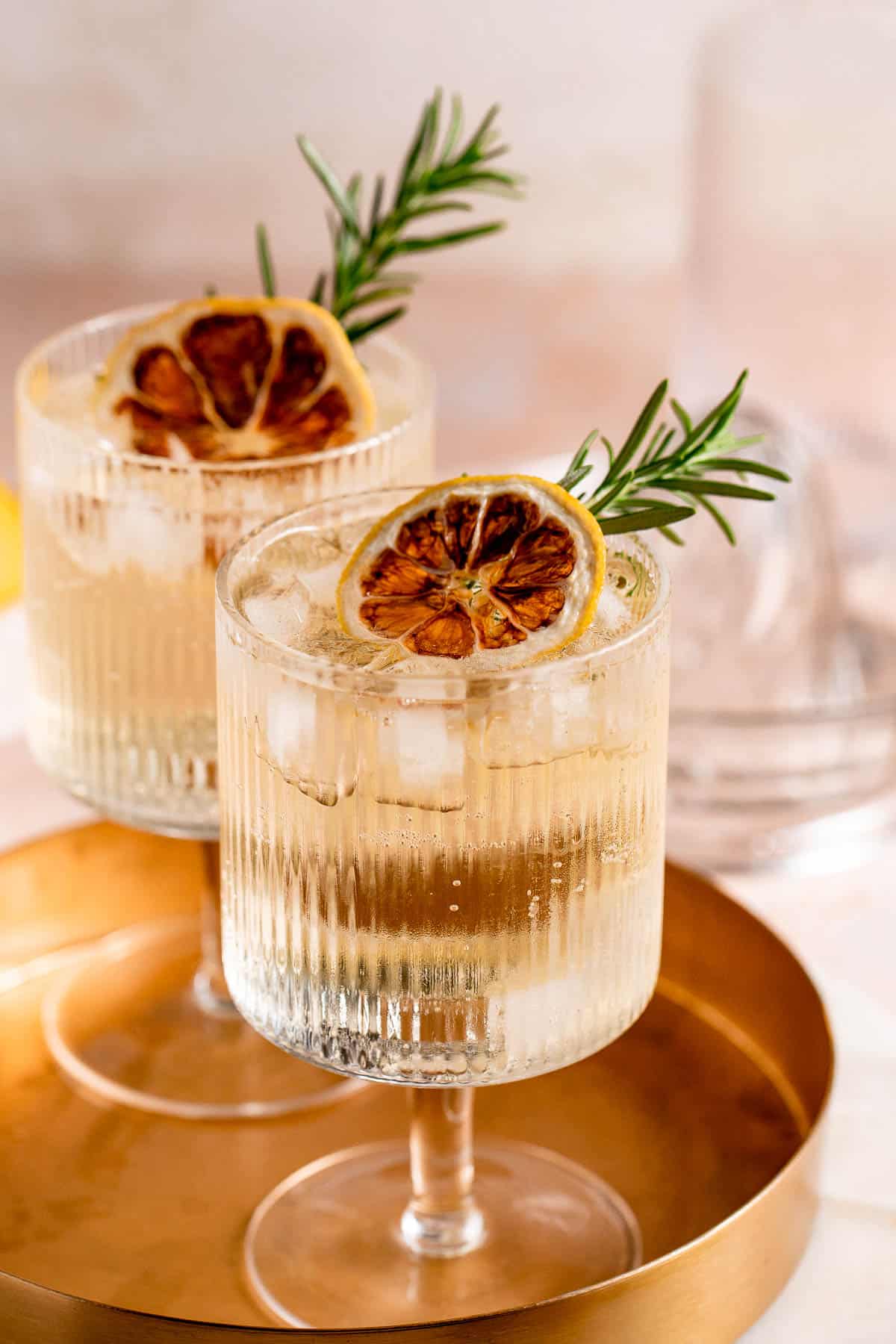 A Whiskey Tonic in a serving glass with ice and fresh herbs.