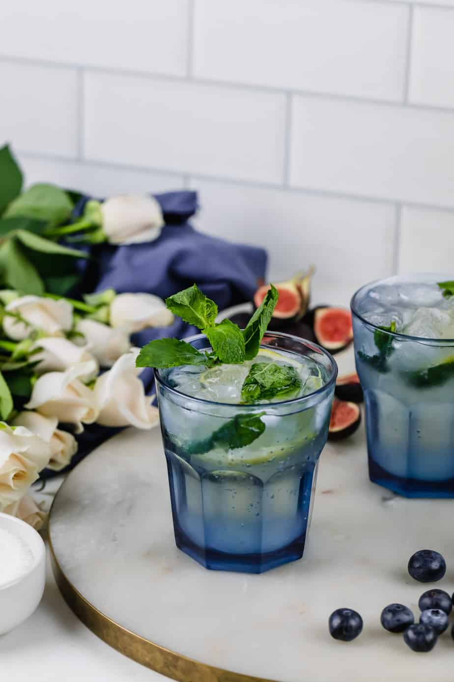 champagne cocktail in blue glasses with mint and roses