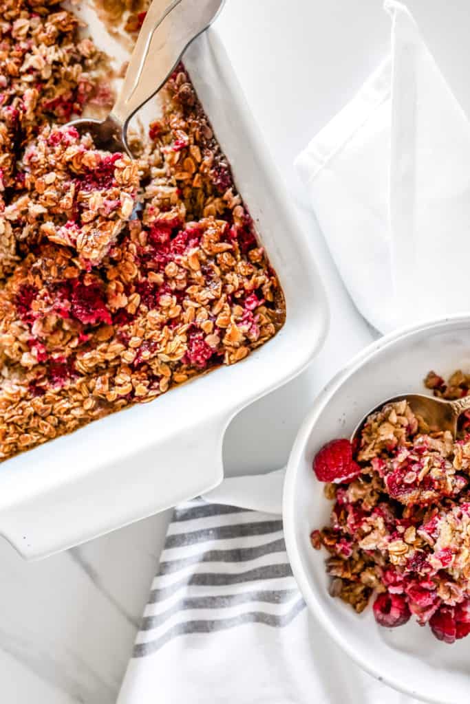 A white dish of baked oatmeal with raspberries.