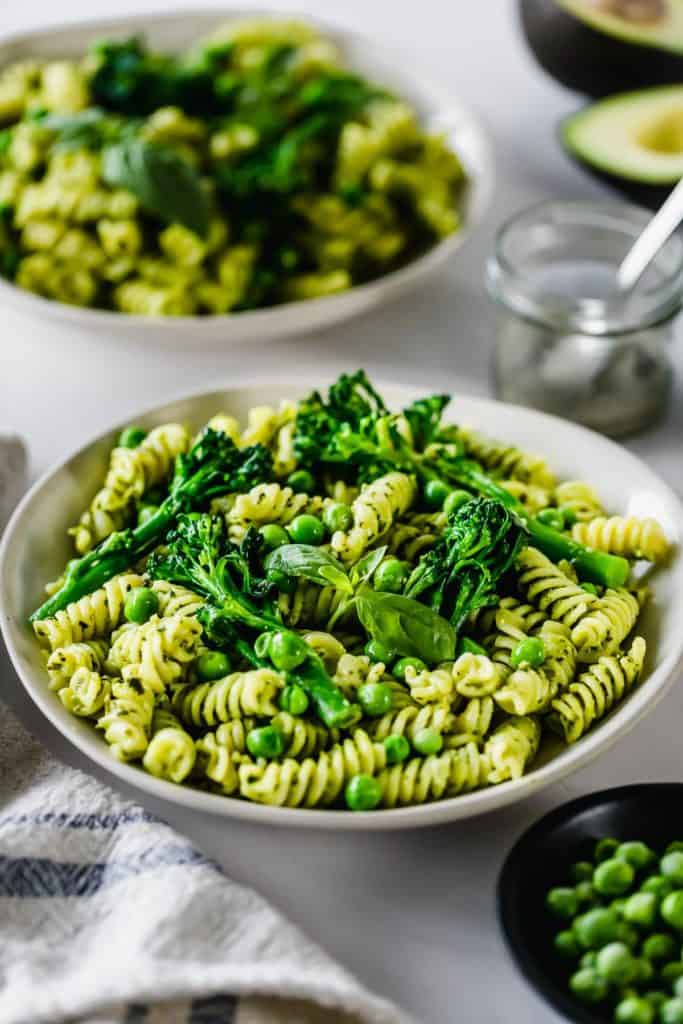 pesto pasta in white bowl with fresh herbs