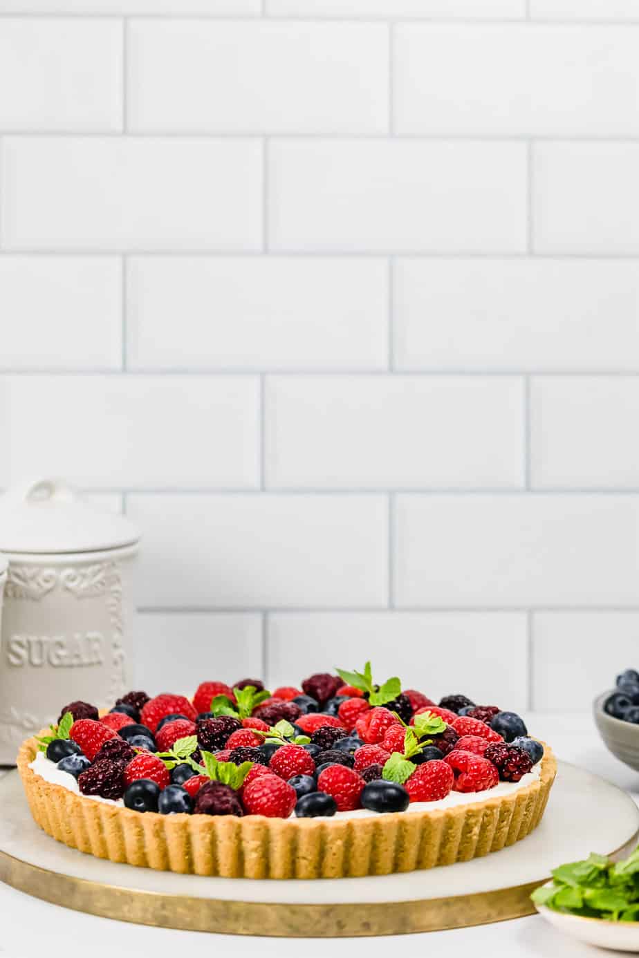 Berry tart on marble board with tile background