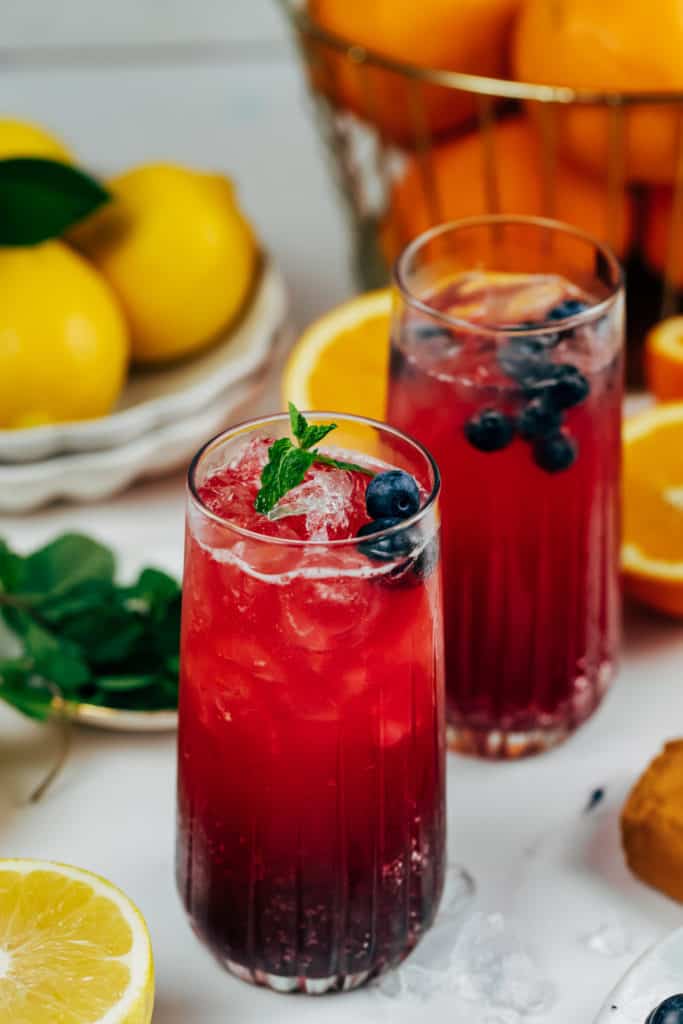 blueberry cocktail with fresh lemons and oranges in the background 
