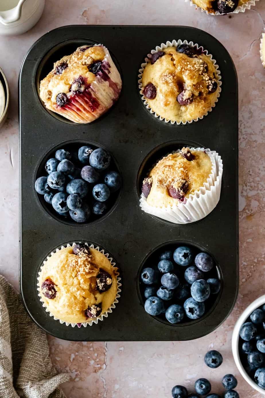 Muffins in a muffin tray with fresh berries.