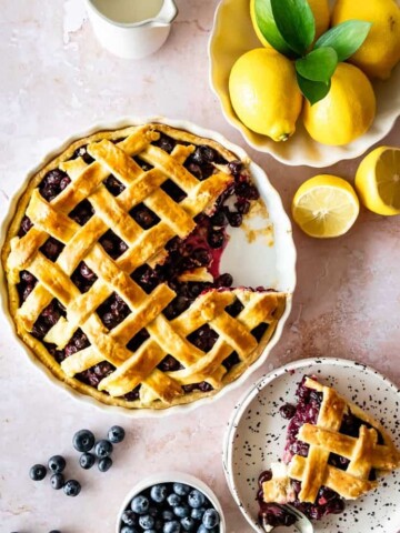 A fresh blueberry pie with one slice served on a plate.