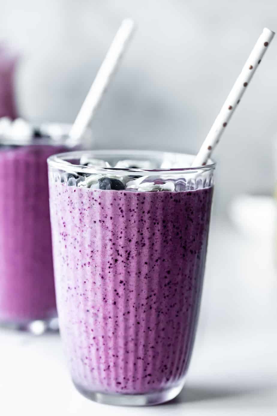 Two smoothies with berries and straws.