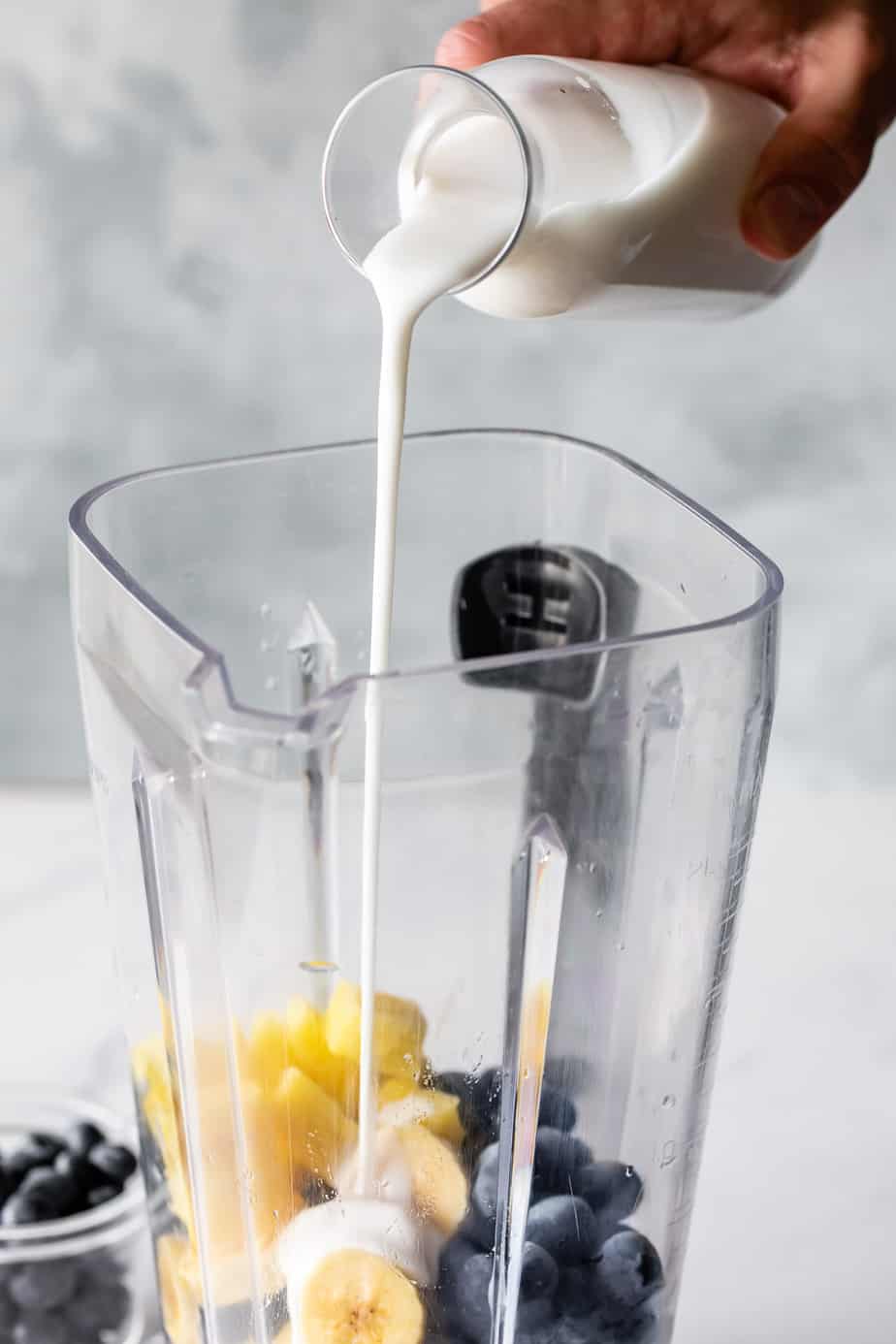 A blender with pineapple and blueberries in it.
